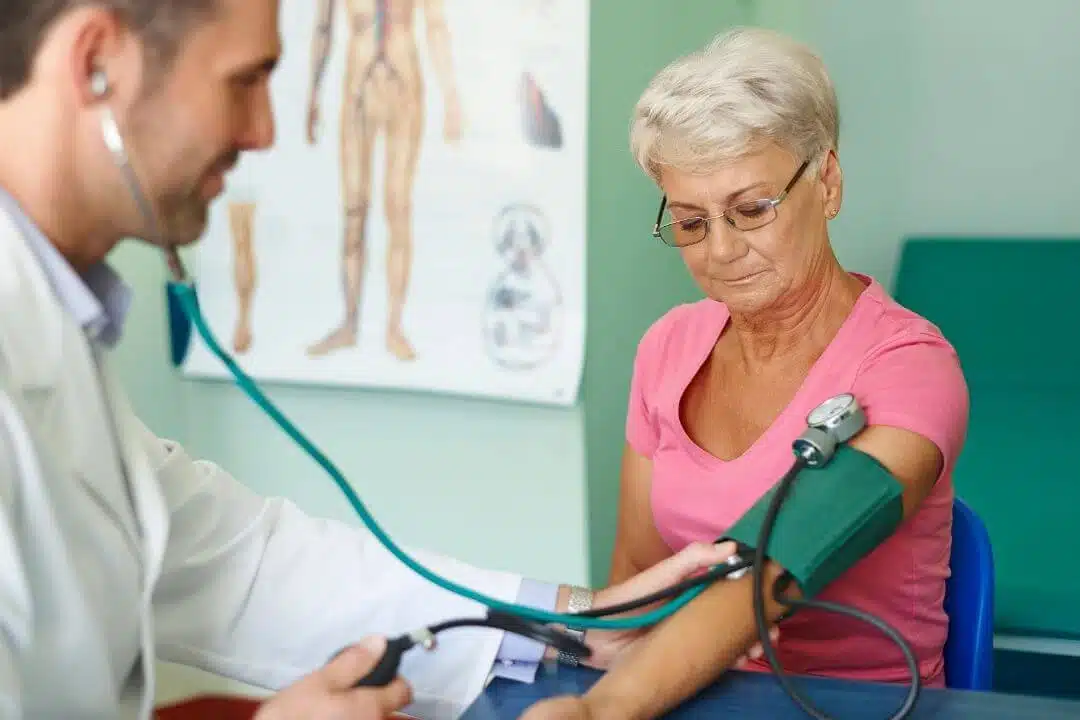Elderly woman receiving blood pressure test.