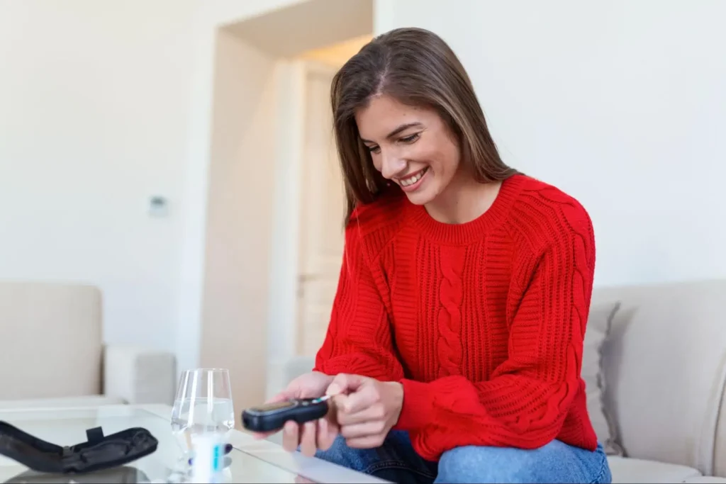 Woman smiling, holding remote at home.